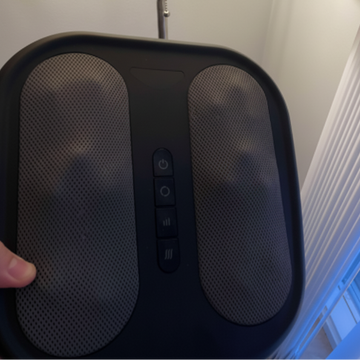 Black massage device held by a hand with a blurred background