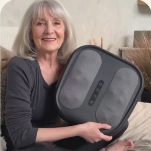 Woman holding a black massage  Bodyrevive 3D pro device on a bed